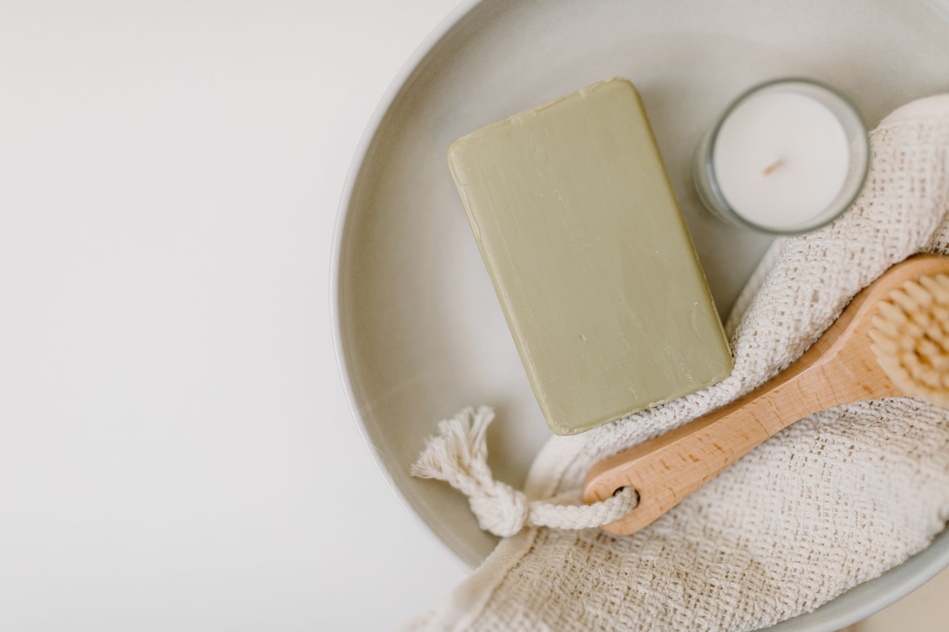A flat lay of soap, candle, brush, and cloth for a calming self-care routine.